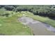 Expansive golf course aerial view featuring a pond with a sandy beach and vibrant green fairways and natural landscape at 103 Golf Terrace Dr, Stockbridge, GA 30281