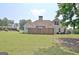 View of backyard with green lawn, chimney, fence and partial view of two story home at 115 Sunderland Cir, Fayetteville, GA 30215