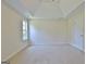 Spacious bedroom showcasing neutral carpeting, a tray ceiling, a window, and a paneled door at 115 Sunderland Cir, Fayetteville, GA 30215