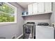 Laundry room with a window, cabinets, shelving, and updated washer and dryer at 1911 Geyser Trce, Lawrenceville, GA 30044