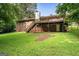 Exterior backyard view of brick home with a wooden deck and stairs down to a concrete patio at 115 Club Cir, Stockbridge, GA 30281