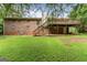 View of brick home showcasing a wooden deck with stairs to concrete patio and lush backyard at 115 Club Cir, Stockbridge, GA 30281