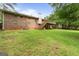 Backyard view of brick home with a wooden deck and lush lawn and trees at 115 Club Cir, Stockbridge, GA 30281