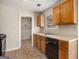 Well-maintained kitchen with double sink, black appliances, wood cabinets, and vinyl flooring at 5575 Pine Gate Dr, Atlanta, GA 30349