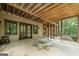 Covered back porch with a picnic table and bench seating overlooks a private wooded backyard at 177 Selfridge Rd, Mcdonough, GA 30252