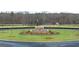 Landscaped traffic circle featuring stone accents, manicured lawn, and mature trees at 352 Sound Cir, Stockbridge, GA 30281