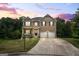 Charming two-story brick home with a well-manicured lawn and a two-car garage under a beautiful sunset at 1492 Bourdon Bell Se Dr, Conyers, GA 30013