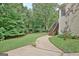 Landscaped backyard with trees, grass, and a walkway leading to stairs and the back of the house at 4135 Coursey Lake Rd, Douglasville, GA 30135