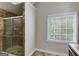 Bathroom featuring a tiled shower with glass door, neutral walls, and a window providing natural light at 90 Thomas Overby Dr, Sharpsburg, GA 30277
