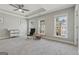 Spacious bedroom featuring tray ceilings, ceiling fan, sitting chair, and three windows with beautiful neighborhood views at 733 Wexford Cove Way, Mableton, GA 30126