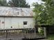 This is the rear exterior featuring a large deck area, peeling paint, and a damaged roof at 11591 Turner Rd, Hampton, GA 30228