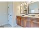 Bathroom with double sink vanity, granite countertops, framed mirrors, and modern lighting fixtures at 117 Elkins Blvd, Locust Grove, GA 30248