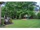 Spacious backyard featuring a deck with grill, lush lawn, mature trees, and a playground at 1952 Sugarstone Dr, Lawrenceville, GA 30043