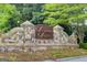 Stone entrance sign for Sugarloaf Springs, surrounded by greenery, welcomes residents and visitors to the neighborhood at 1952 Sugarstone Dr, Lawrenceville, GA 30043