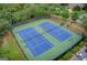 A fenced-in tennis court with a blue surface is well-maintained and includes lighting for nighttime play at 1952 Sugarstone Dr, Lawrenceville, GA 30043