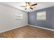 Bedroom features wood-look floors, a ceiling fan, and two windows letting in natural light, offering a cozy ambiance at 103 Chipstone Ct, Peachtree City, GA 30269