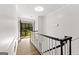 Hallway with white railings, wood-look floors, and open balcony doors framing a lush outdoor view at 103 Chipstone Ct, Peachtree City, GA 30269