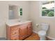 Bathroom with wood vanity and large mirror, toilet and window for natural light at 778 Leguin Mill Rd, Locust Grove, GA 30248
