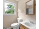 Bathroom with a wood vanity, white toilet, and large window offering natural light at 778 Leguin Mill Rd, Locust Grove, GA 30248
