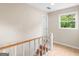Upstairs hallway with a white banister and a large window, neutral walls and trim at 778 Leguin Mill Rd, Locust Grove, GA 30248
