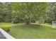 Large, grassy backyard with a mature tree with pink blossoms, a gazebo, and a white fence at 3100 Meadow Trl, Loganville, GA 30052