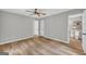 Bedroom features wood-look flooring, ceiling fan, and a view into an adjoining bathroom at 3100 Meadow Trl, Loganville, GA 30052