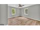 Bright bedroom with wood-look floors, two windows, ceiling fan, and neutral wall color at 3100 Meadow Trl, Loganville, GA 30052