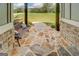 Relaxing front porch featuring a stone floor, decorative bench, and inviting view of the lawn at 3076 East Lake Rd, Mcdonough, GA 30252