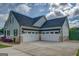 Three-car garage featuring white doors that compliment the home's light green siding and stone accents at 3076 East Lake Rd, Mcdonough, GA 30252