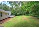 Lush backyard with green lawn and wooded area, featuring a deck perfect for outdoor entertaining at 400 Kenny Ln, Temple, GA 30179