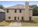 Back exterior view of a tan home with a brick foundation, a concrete patio and a green lawn at 1001 Hartwell Rd, Locust Grove, GA 30248