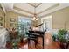 Elegant dining room with hardwood floors, tray ceiling, chandelier, grand piano, and natural light at 1422 New Holland Cir, Mcdonough, GA 30252