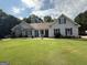 Charming single-story home with gray siding, stone accents, mature landscaping, and a lush green lawn at 1422 New Holland Cir, Mcdonough, GA 30252