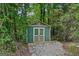 Backyard shed surrounded by dense trees with gravel path, providing storage space at 1422 New Holland Cir, Mcdonough, GA 30252