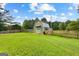 View of the backyard barn/outbuilding surrounded by a beautiful lawn and wood fence at 135 Cherokee Pl, Fayetteville, GA 30215