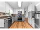 Well lit kitchen with wood floor, stainless steel appliances, and gray and white cabinets at 135 Cherokee Pl, Fayetteville, GA 30215