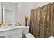 A well-lit bathroom with an elegant vanity, toilet, and a decorative shower curtain at 140 Canyons, Hampton, GA 30228