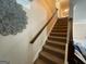 Carpeted staircase with wooden railing and decorative wall art, creating a stylish transition between floors in the home at 1141 Norsworthy Ml, Hampton, GA 30228