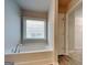 Bathroom with a garden tub beneath a window, light walls, and wood style floor at 3712 Upland Dr, Mcdonough, GA 30253