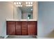 Bathroom vanity with double sinks, warm wood cabinetry, a large mirror, and modern lighting at 3712 Upland Dr, Mcdonough, GA 30253