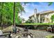 A backyard with a stone firepit, patio furniture, a large grassy area, and a home's exterior under a blue sky at 1605 Cascade Overlook, Peachtree City, GA 30269