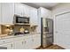 Kitchen featuring stainless fridge, modern appliances, tile backsplash, granite countertops, and white cabinets at 1605 Cascade Overlook, Peachtree City, GA 30269