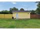 A yellow backyard shed with a white door sits on a well-maintained lawn enclosed with a wooden fence at 250 Stallsworth Rd, Mcdonough, GA 30252