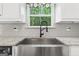 Close-up of a stainless steel farmhouse sink with modern faucet and granite countertops at 2565 Aaron Ct, Loganville, GA 30052