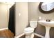 A simply designed bathroom featuring a toilet, vanity with a pedestal sink and a dark shower curtain at 543 Wynn Rd, Mcdonough, GA 30252