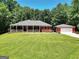 Charming red brick home featuring a welcoming front porch and lush green lawn with a detached garage at 543 Wynn Rd, Mcdonough, GA 30252