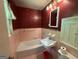 Bathroom featuring a pink tile bathtub, sink, mirror, and fixtures at 402 Stone St, Oxford, GA 30054