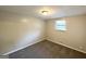 Clean and simple bedroom with a single window, neutral carpet, and base molding at 5670 Bob White Ln, Douglasville, GA 30135