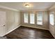 Cozy bedroom with wood-look flooring, base molding, three windows, and a white door at 5670 Bob White Ln, Douglasville, GA 30135