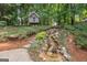 Beautiful backyard featuring a custom treehouse, stone steps and small waterfall surrounded by lush greenery at 220 Lavender Oasis, Peachtree City, GA 30269